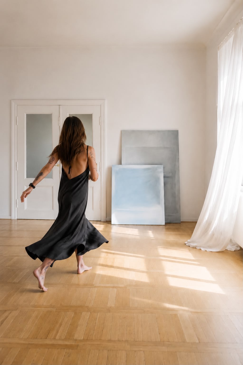 Ada Kamińska moving through a light-filled room beside paintings from the Spaces / Non-Spaces series.